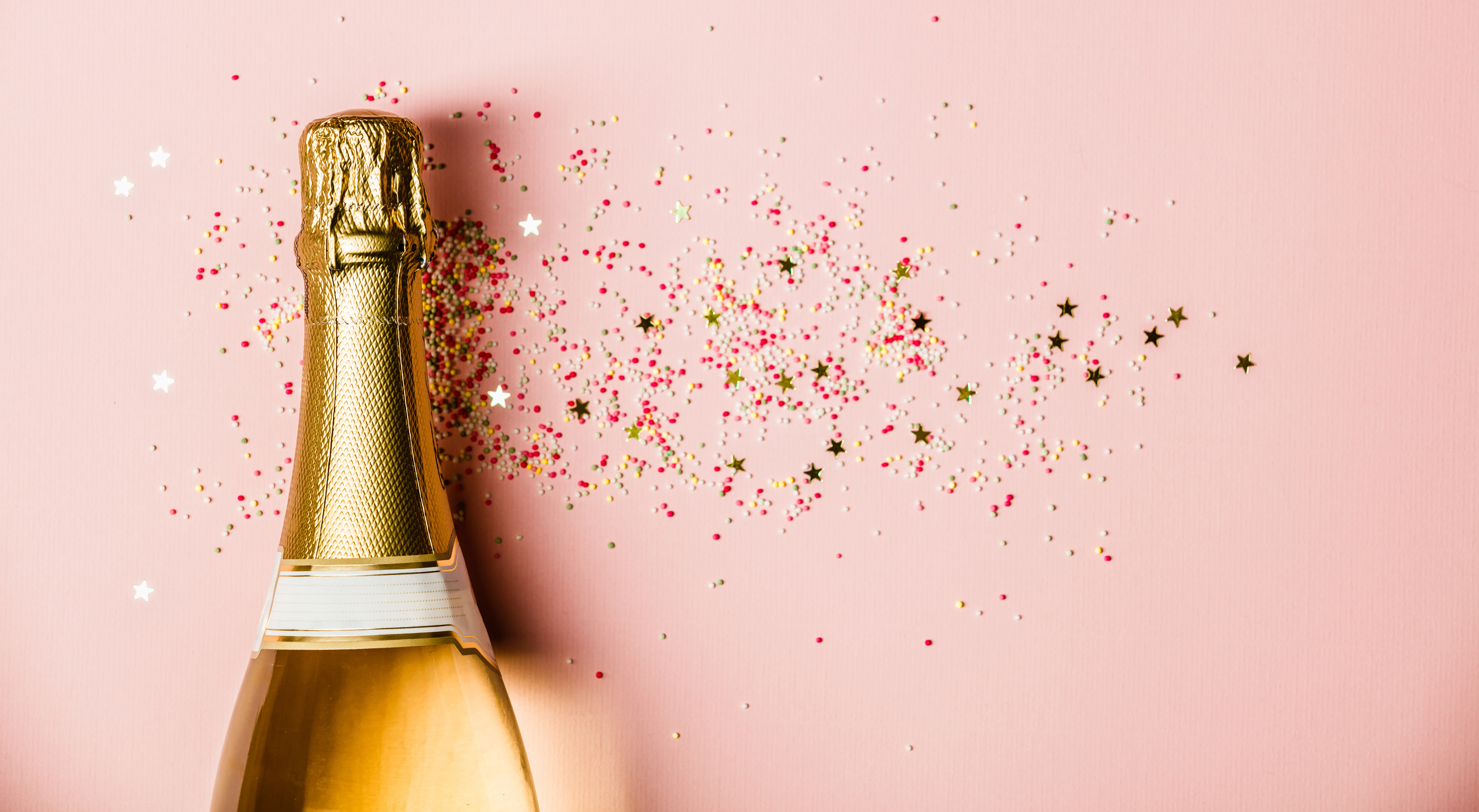 Champagne Bottle with Sprinkles on Pink Background